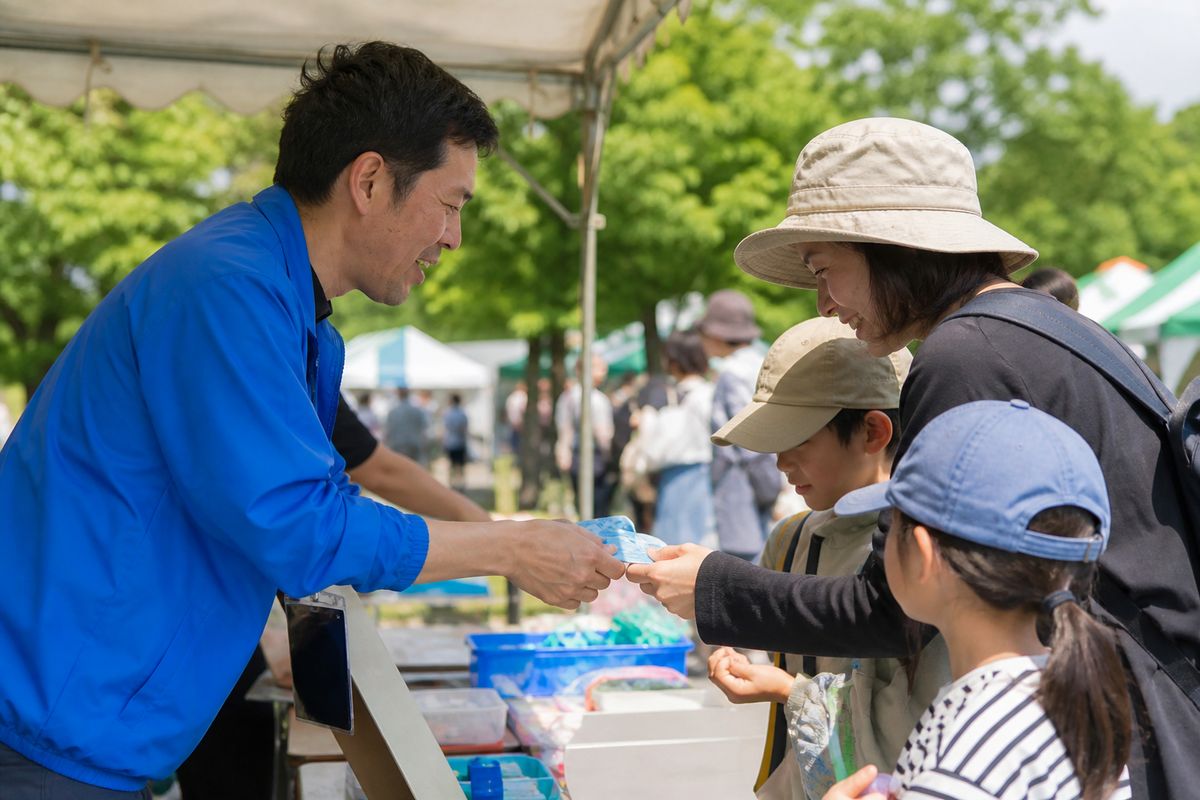 地域の祭り会場でスタッフと来場者が受付でやり取りする様子