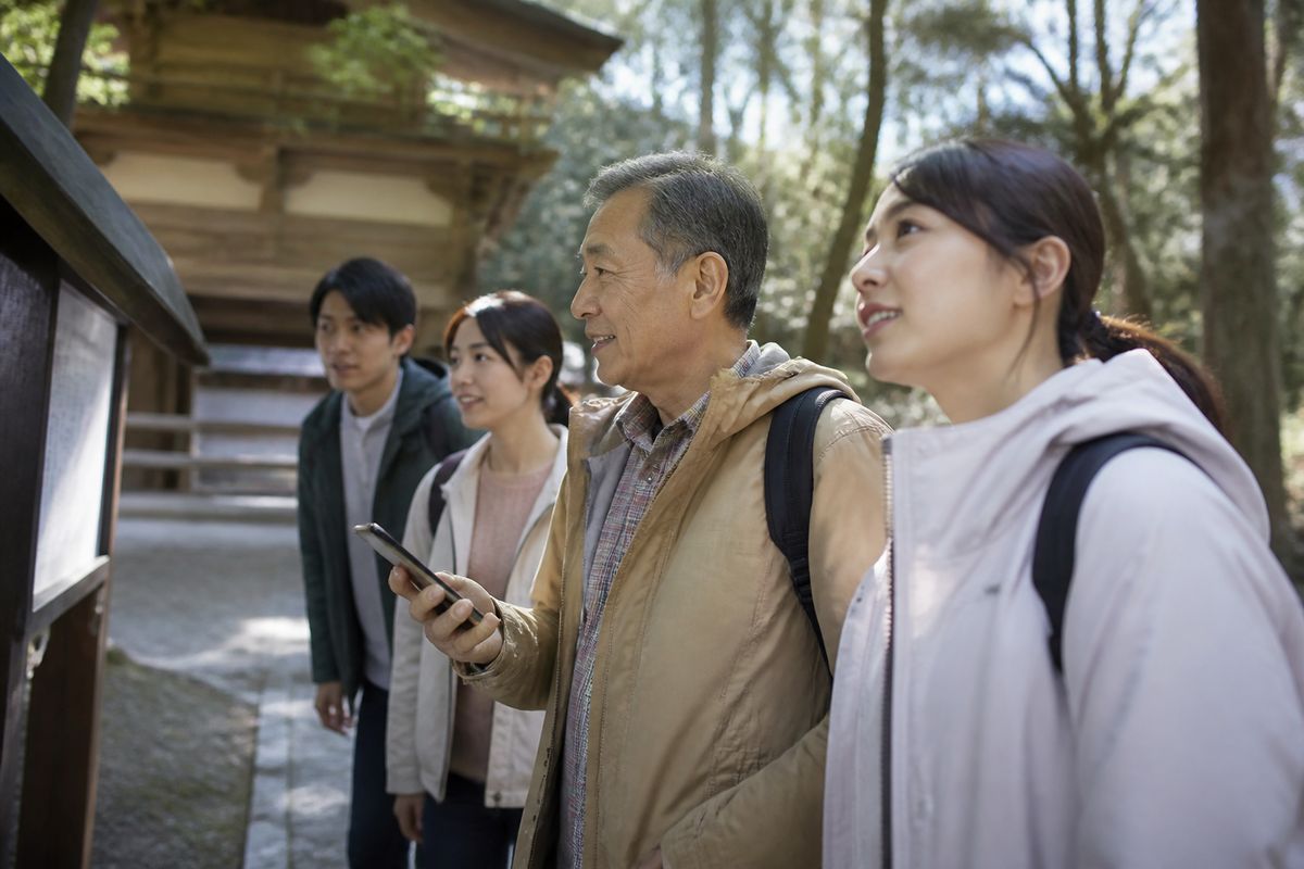 スマートフォンを片手に案内板を確認しながら歩く高齢者と若い世代の参加者
