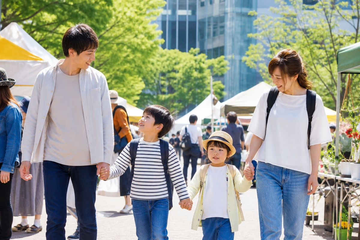 屋外の広場で開催されているイベント会場を家族連れが楽しそうに歩いている様子