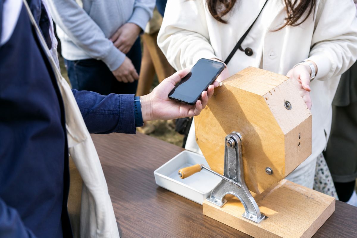 屋外イベントでスマートフォンをかざしてくじを引いている来場者の手元