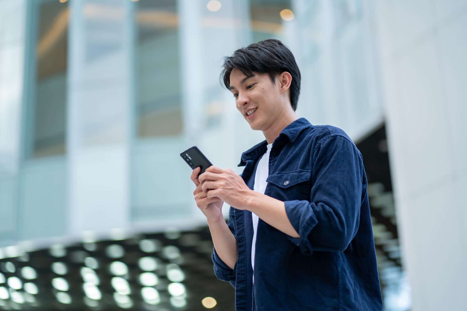 屋外でスマートフォンの通信状況を確認しながらデジタルスタンプラリーに参加する様子