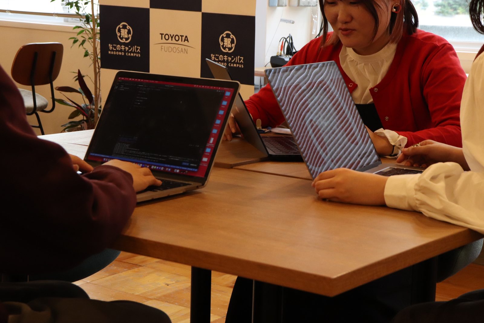 でらっくじのメンバーがPCを開いてデジタルスタンプラリーの企画と予算を詰めている様子
