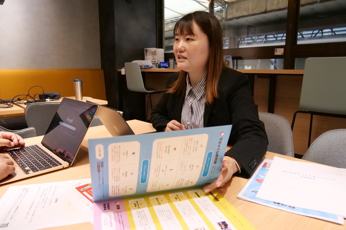 打ち合わせで資料を見せながら説明する高木さん