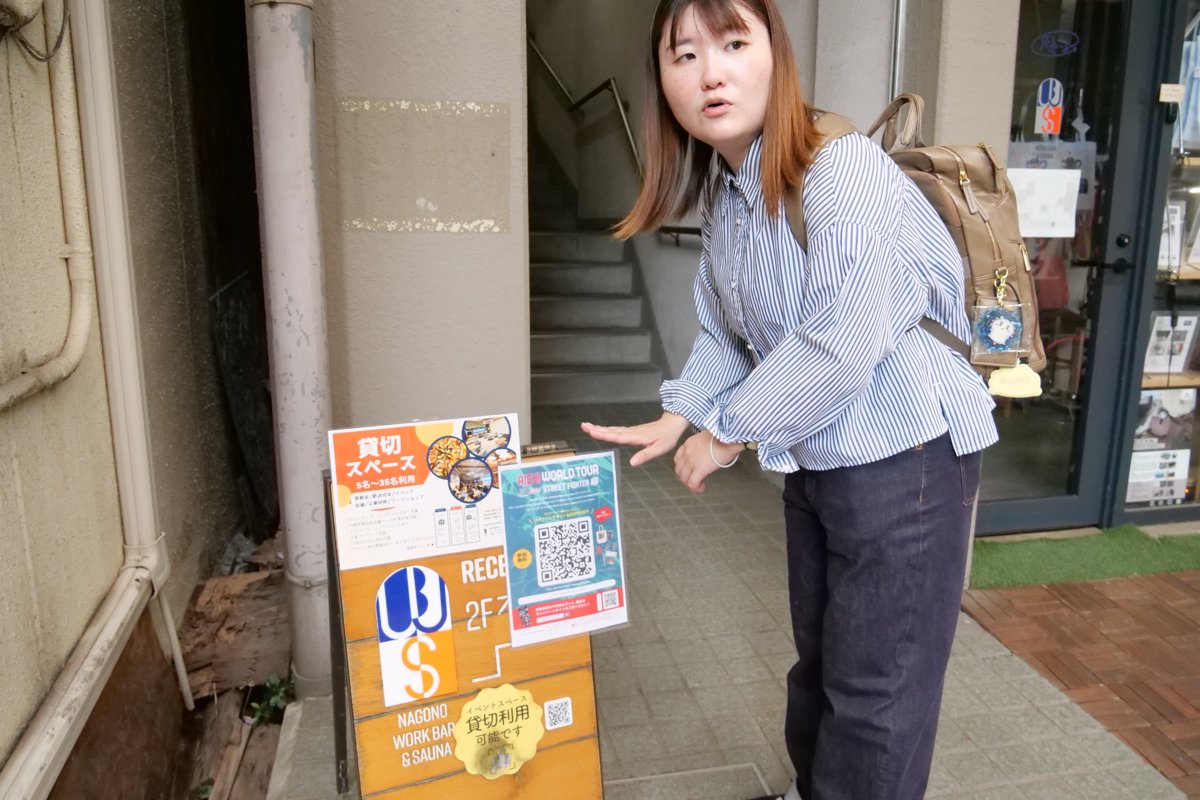 店先に貼ったQRコードの掲示物を手で示しながら説明する高木さん
