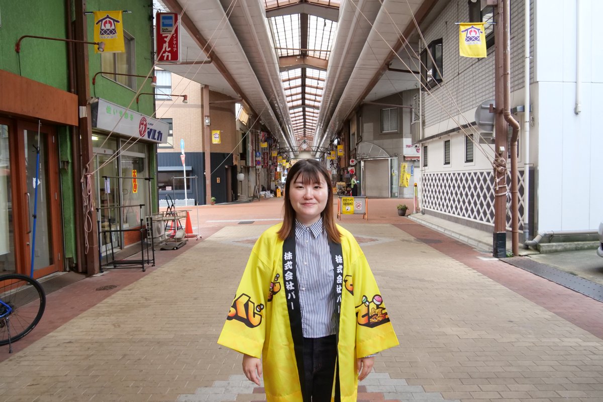 でらっくじのはっぴを着て、円頓寺商店街に立つ高木さん