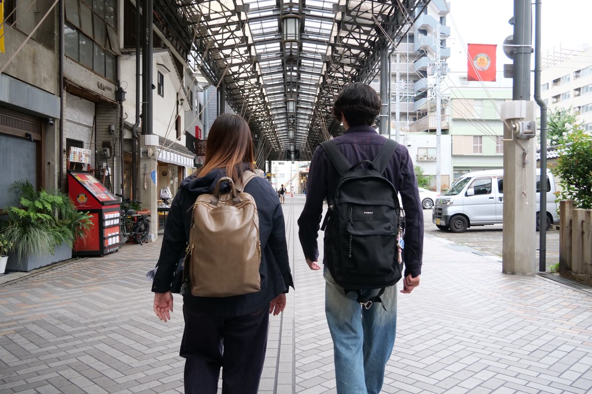 商店街のアーケードを歩いて、スポットを巡る高木さん